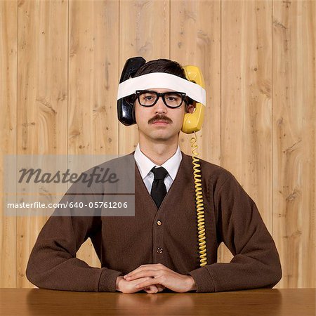 Businessman with telephones strapped to head in office