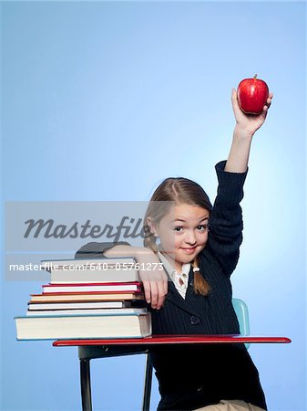 Studio portrait of girl (10-11) with stack of books and apple