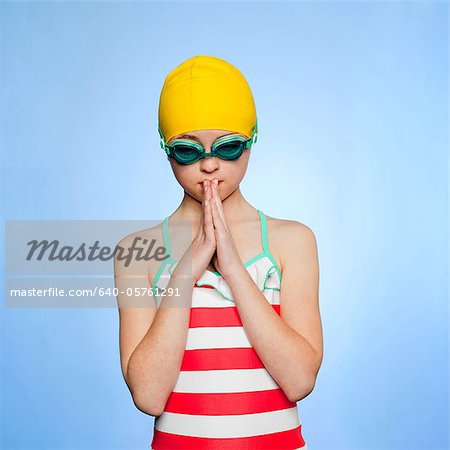 Studio shot of girl (10-11) wearing swimsuit, swimming cap and swimming goggles