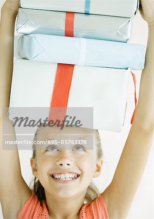Jeune fille tenant un pile de cadeaux sur la tête