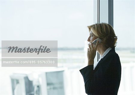 Femme à l'aide de téléphone portable à l'aéroport, fenêtre