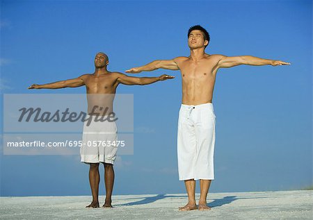 Two men doing relaxation exercises on the beach