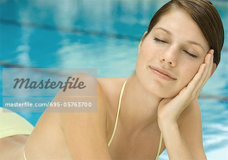 Femme au bord de la piscine, les yeux fermés