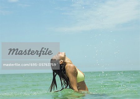 Frau, stehend im Meer, Kopf nach hinten und Wassertropfen in der Luft nach dem nassen Haaren umkehren