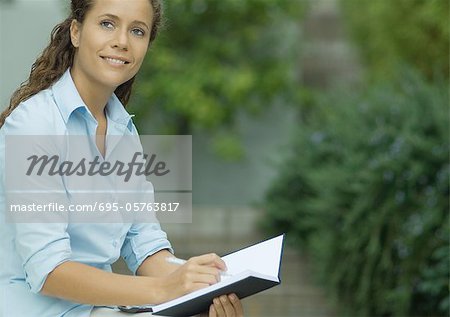 Jeune femme écrit dans le livre, souriant