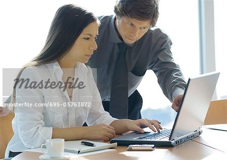 Businesswoman and man working with laptop