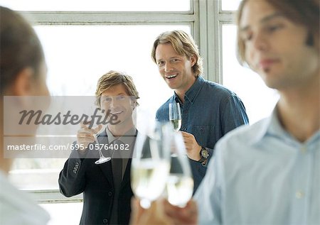 Hommes brandissant des verres de champagne au cours de la soirée cocktail