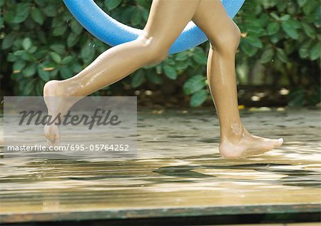 Child running by edge of pool, cropped view of legs