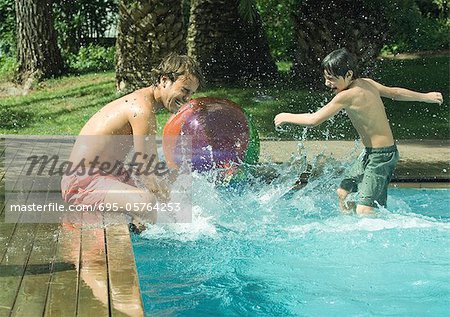 Father and son splashing in swimming pool