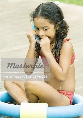 Girl sitting in ring, putting snorkel in mouth