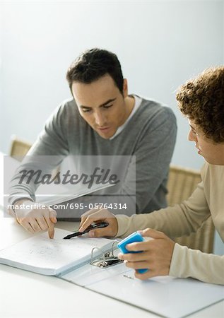 Man helping teenage son with homework