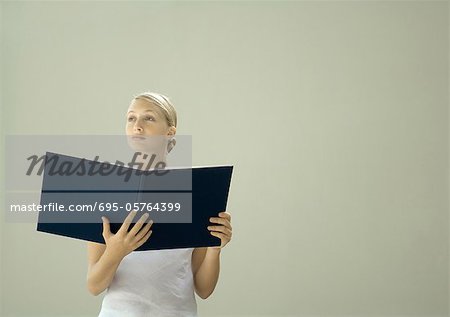 Woman holding open book, looking away