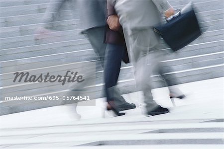 Businessman and woman walking, waist down, blurred motion