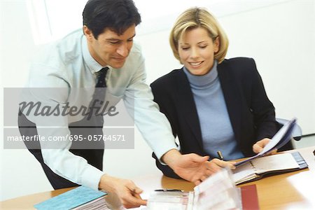Business colleagues, man leaning over woman's shoulder