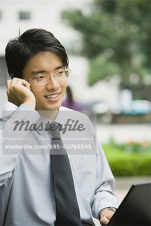 Homme d'affaires avec ordinateur portable et téléphone portable à l'extérieur