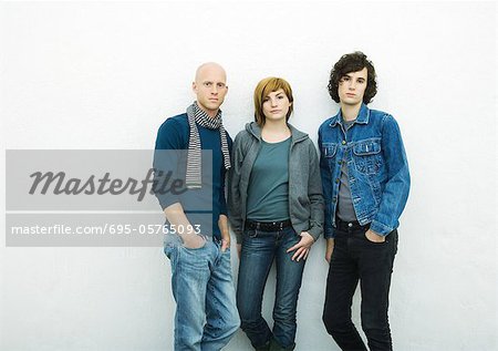Drei junge Erwachsene an die Wand gelehnt Blick in die Kamera, Porträt, Weißer Hintergrund
