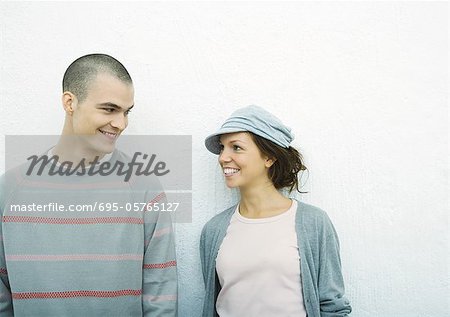 Jeune couple debout côte à côte, portrait, fond blanc
