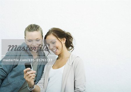 Young female friends looking at cell phone together