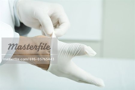 Doctor putting on latex gloves, close-up