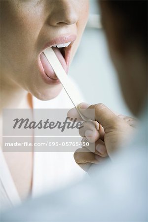 Doctor holding down woman's tongue with tongue depressor