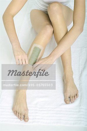 Woman applying cold wax strips, partial view