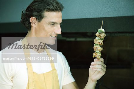 Homme brandissant kebab grillé