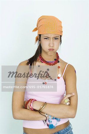 Teen girl wearing lots of accessories, arms folded, blowing cheeks out, portrait