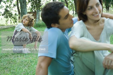 Boy sitting on ball, parents in foreground