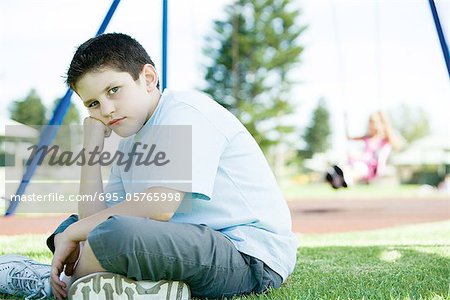 Enfant assis sur le terrain de jeu