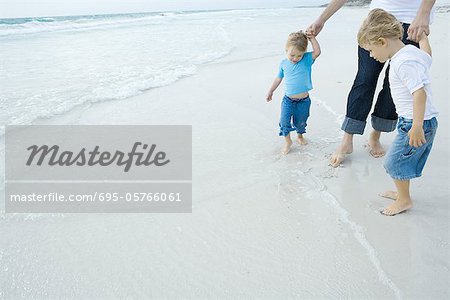 Père et enfants marchant dans surf