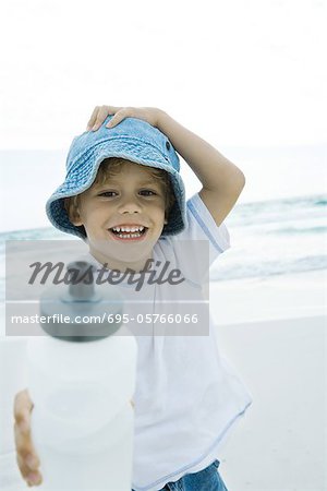 Garçon levant la bouteille d'eau sur la plage