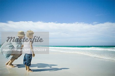 Frau und Knabe stehen am Strand, mit Blick auf die Wellen