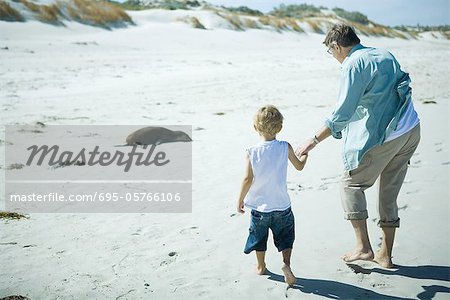 Enfant et adulte marchant sur le sable
