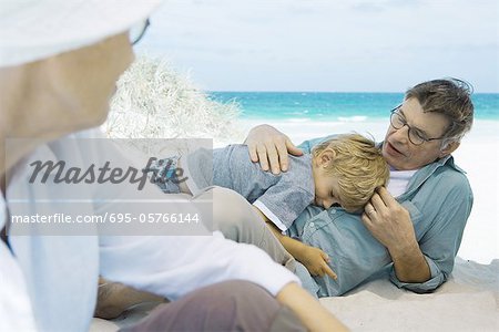 Famille sur la plage, garçon, reposant sur le grand-père
