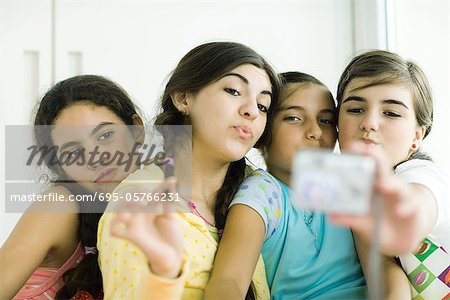 Young female friends with make-up looking at selves in hand mirror