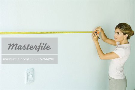 Femme à l'aide de ruban à mesurer sur le mur