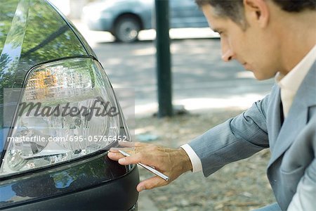 Mature man in suit inspecting car