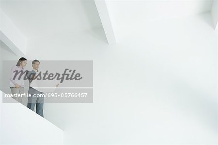 Young woman standing with architect, looking over large bare interior