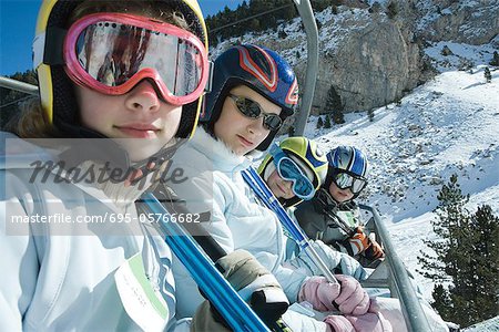 Young skiers on chair lift, smiling at camera