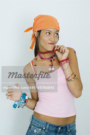 Teenage girl wearing lots of jewelry, looking away, portrait