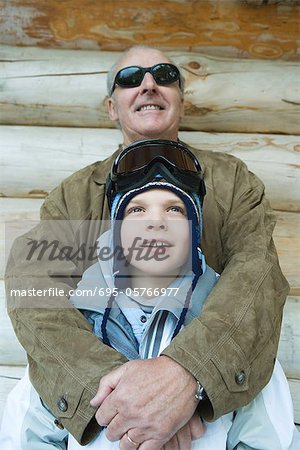 Grandfather embracing grandson, dressed in winter clothing, portrait