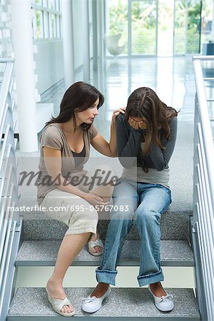 Mutter beruhigend Tochter im Teenageralter, sitzen auf Schritte
