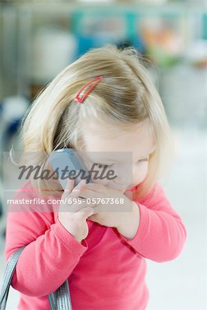 Blonde toddler girl holding cell phone to ear