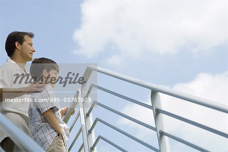 Vater und Sohn durch Geländer ständigen low Blick auf Himmel, Angle view