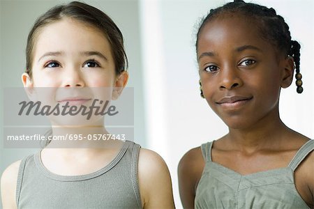 Two girls side by side, one smiling at camera