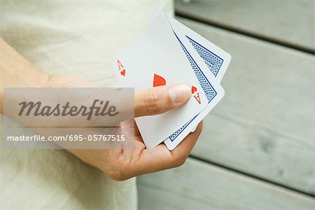 Woman playing card game, cropped view of hand holding cards