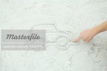 Teenage boy drawing car in sand, cropped view