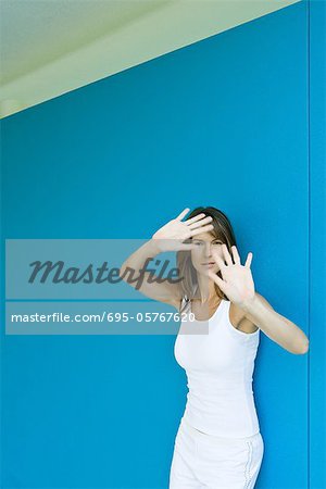 Femme appuyé contre le mur, main dans la main vers le haut face à face, regardant la caméra