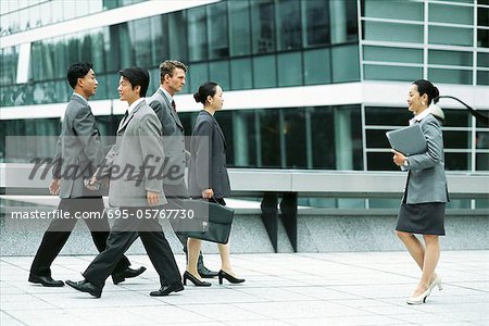 Male and female professionals walking on busy sidewalk, side view