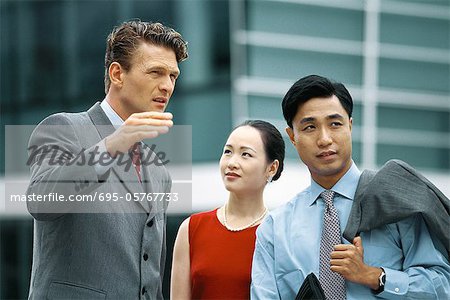 Business associates standing outdoors, talking, man gesturing with hand